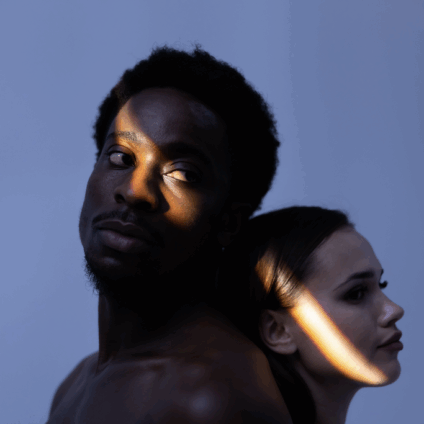 Afro man en brunette vrouw in de schaduw tegen een grauwe achtergrond ter illustratie van de relatieproblemen