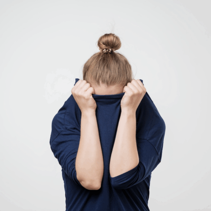 vrouw met knotje trekt de trui over har gezicht uit schaamte