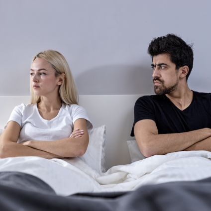 Man en vrouw liggen afstandelijk in bed, symbool voor relatie zonder intimiteit of broer-zus relatie