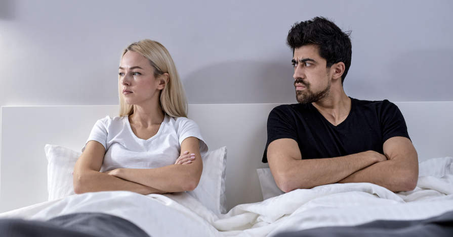 Man en vrouw liggen afstandelijk in bed, symbool voor relatie zonder intimiteit of broer-zus relatie