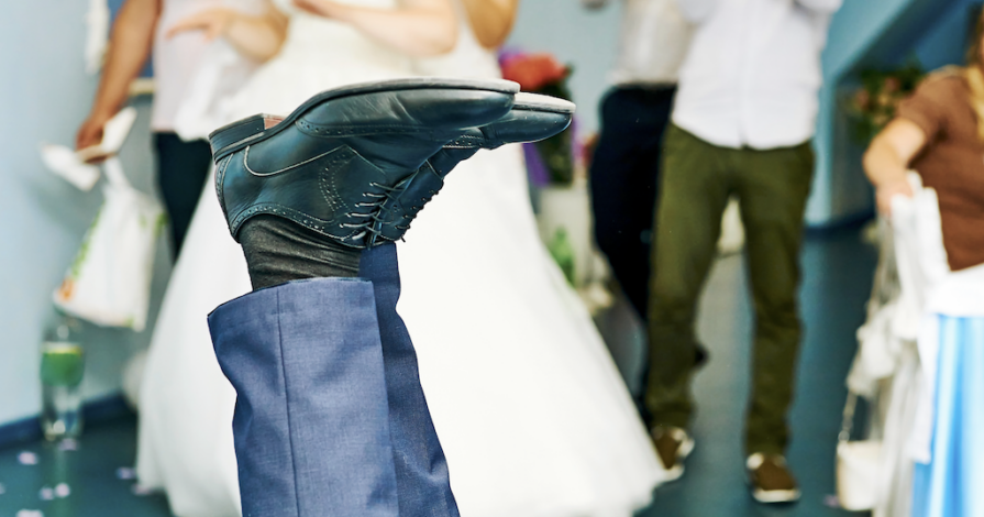 Man struikelt tijdens bruiloft terwijl bruid op de achtergrond staat, symbool voor relatiebreuk en scheiding