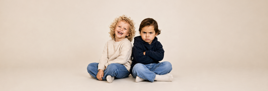 Twee kinderen met een verschillende emotionele reactie op dezelfde situatie. Het ene kind lacht, het andere kijkt boos. Beeld over hoe kinderen een scheiding verschillend kunnen ervaren.
